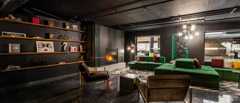 A modern lounge area with a fireplace, green sofas, and a variety of decorative items on shelves.