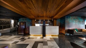 A modern lobby with a wooden ceiling, a reception desk, a sofa, and a patterned floor. - Lelux Hotel (Montreal)