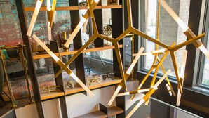 A modern interior with a geometric light fixture, a staircase, and a view of the outside. - Lelux Hotel (Montreal)