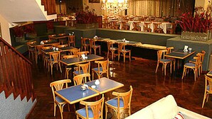 En restaurang med flera bord och stolar, ett trägolv och en trappa.