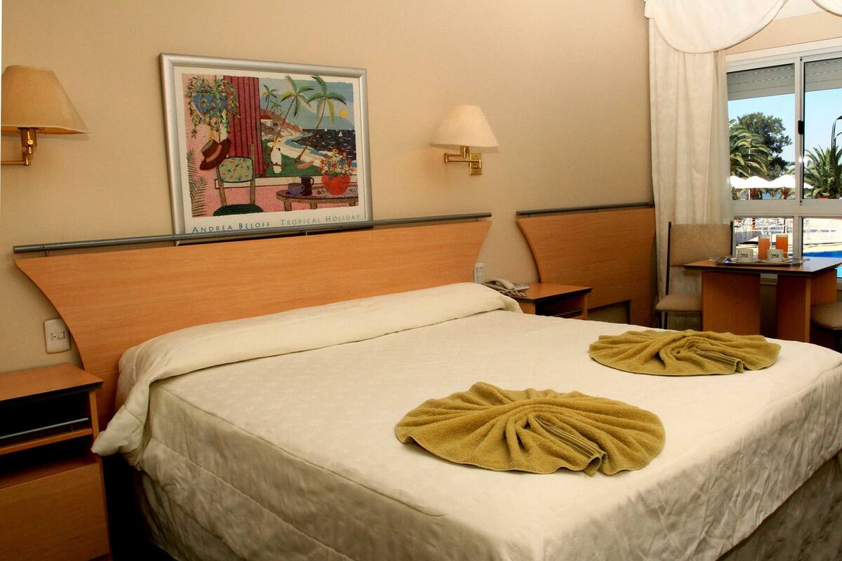 A hotel room with a bed, a desk, a chair, and a window with curtains.