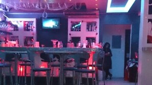 Una zona de bar con barra, taburetes y una pantalla de televisión.