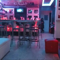 A bar area with a counter, stools, and a television screen.