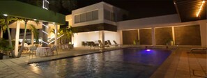 A modern pool area with lounge chairs and a covered seating area.