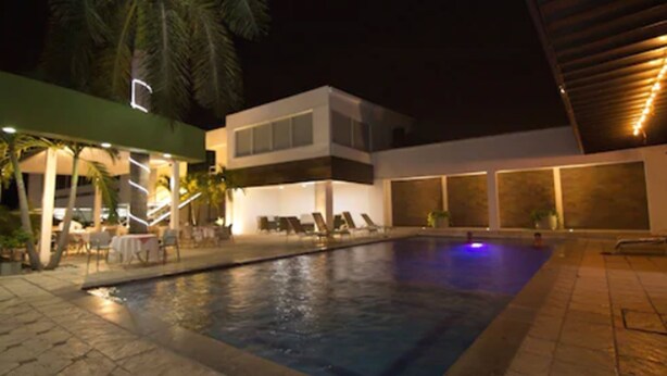 Un hotel moderno con piscina, sillas de descanso y un patio cubierto.