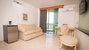 Un espacio habitable compacto con sofá, una mesita, una silla y un refrigerador.