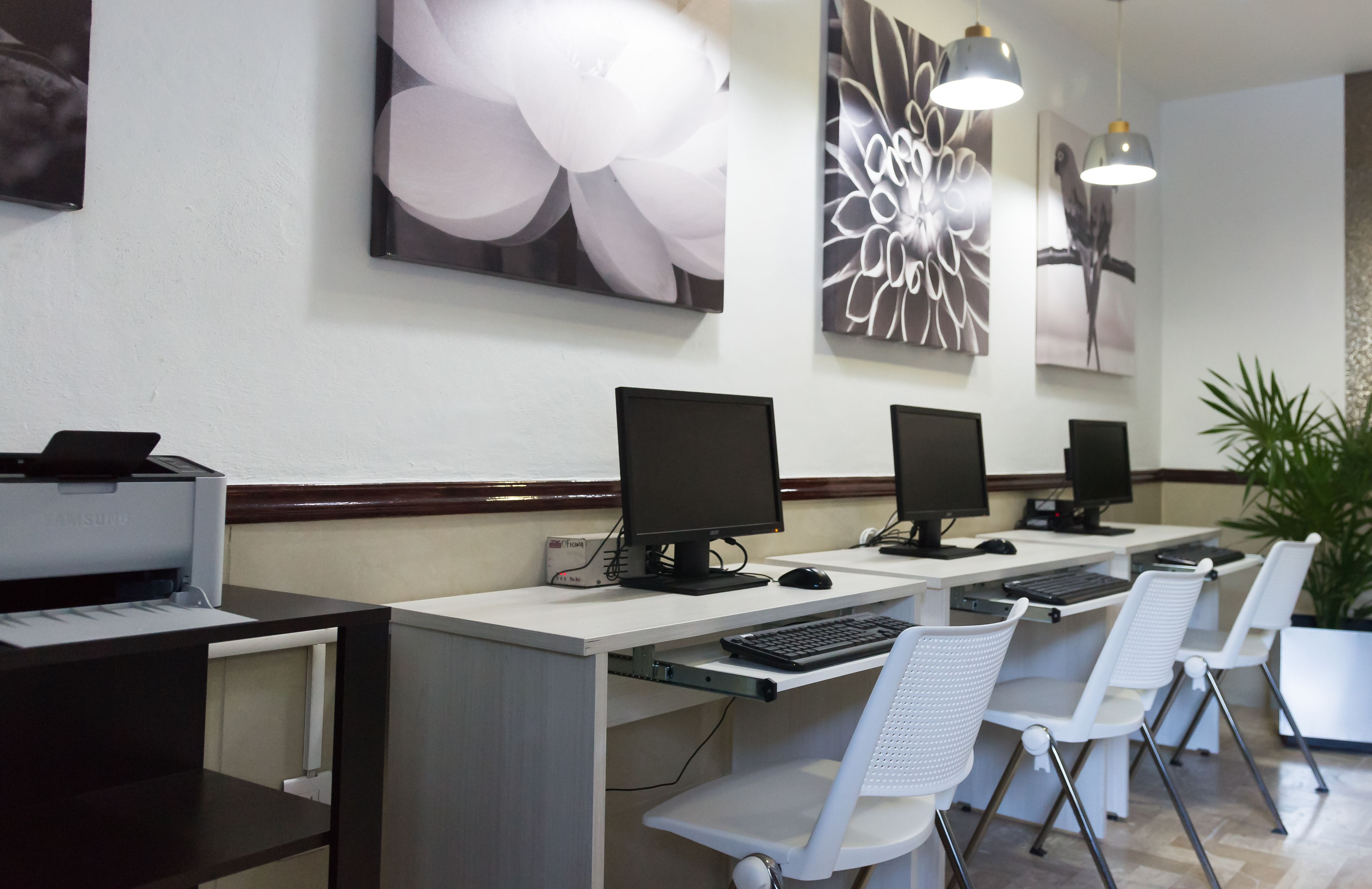 A reception area with multiple computer workstations, white chairs, and artwork on the walls.