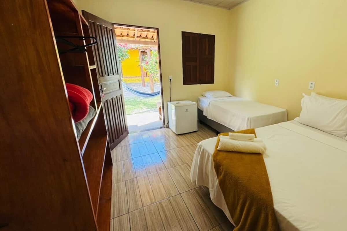 A room with two beds, a small table, a heater, and a door leading to an outdoor area.