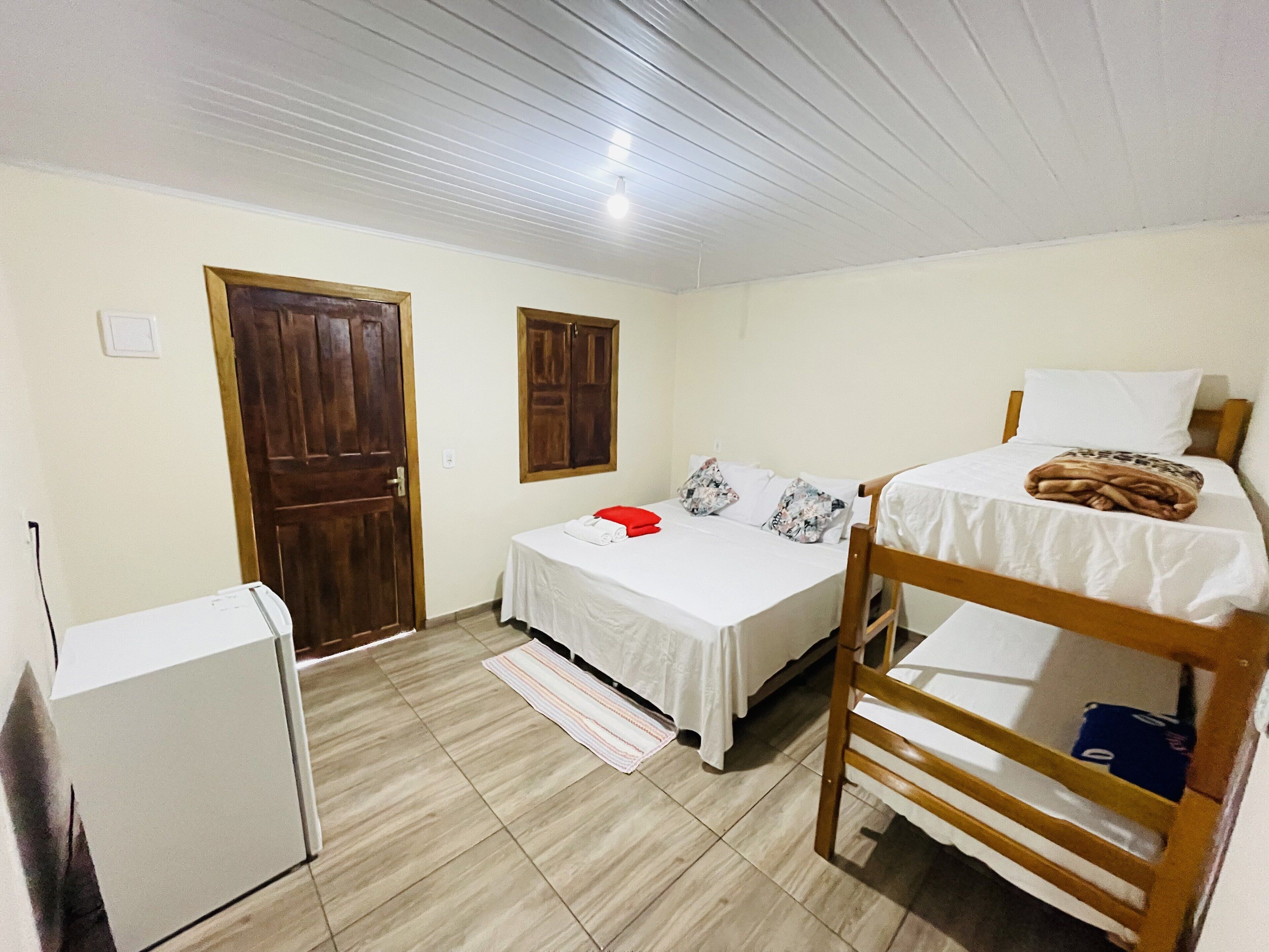 A room with two beds, a wooden door, and a small white appliance.
