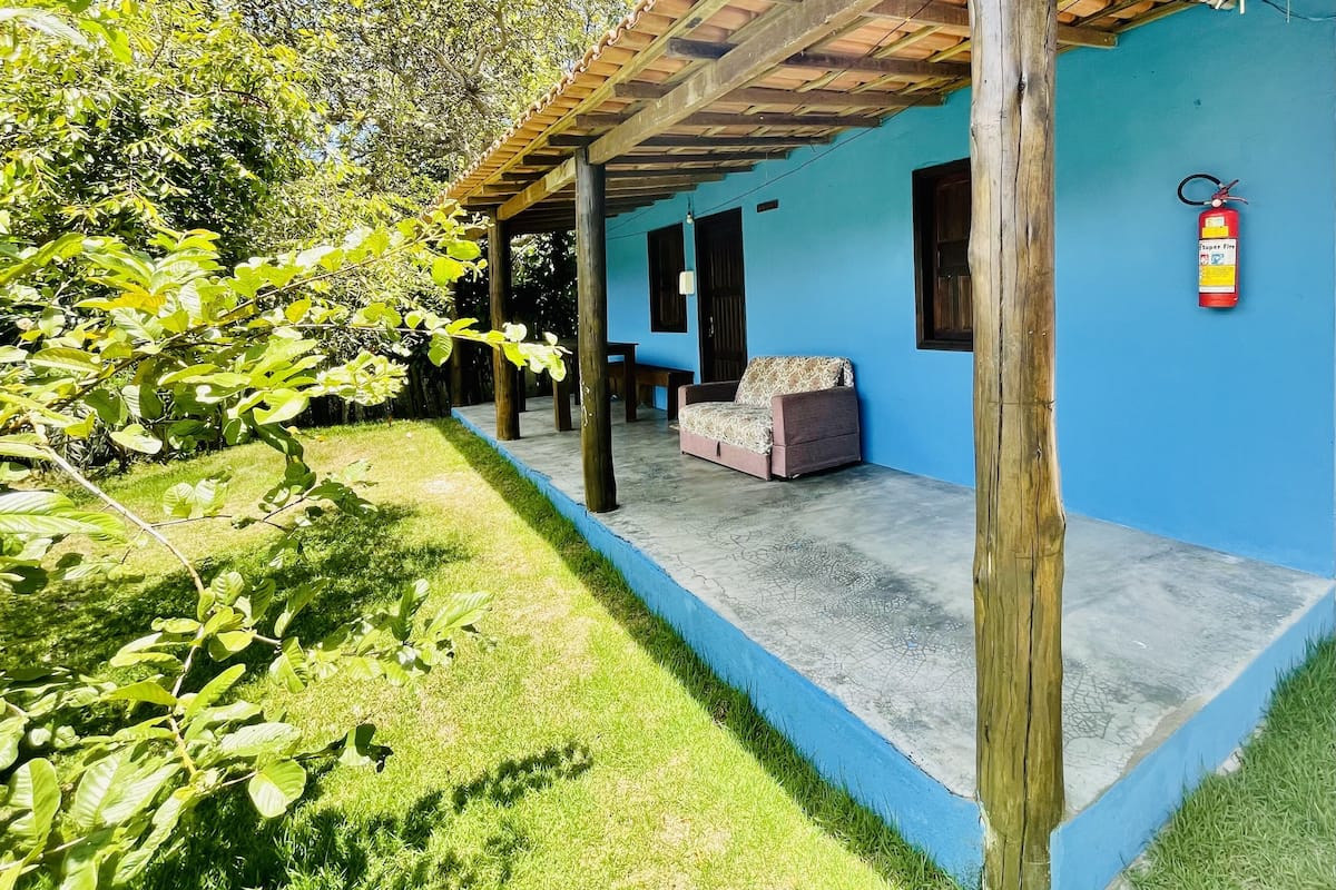 A covered outdoor area with a blue wall, a fire extinguisher, and a sofa.