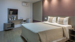 Une chambre d’hôtel moderne équipée d’un grand lit, d’un bureau, d’une chaise et d’un téléviseur.
