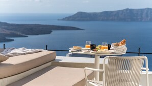 Balcón con mesa lista para el desayuno, con vista a un cuerpo de agua y tierra a lo lejos.
