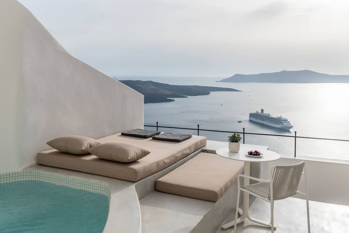Varanda com piscina, área de estar e vista para o mar e um navio de cruzeiro.