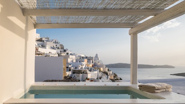 Un área de piscina con vistas a edificios blancos y al mar.