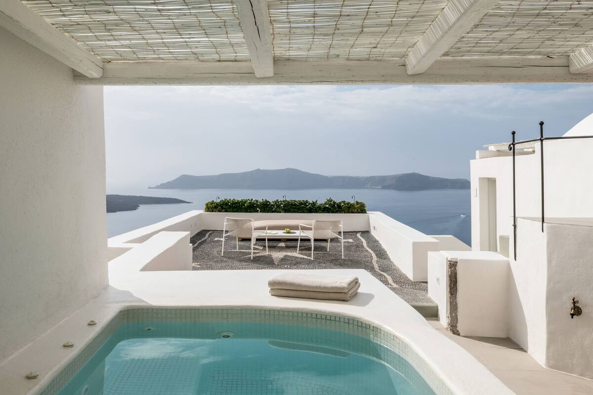 Terraço no telhado com piscina, área de estar e vista para o mar e montanhas.