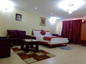 Una habitación de hotel con cama, sofá, mesa de centro y candelabro.