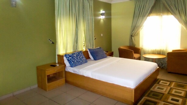 Habitación de hotel con una cama grande, dos mesitas de noche, una pequeña mesa redonda y una silla.