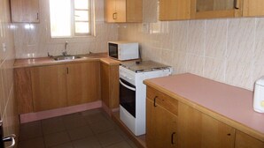 Una cocina con armarios de madera, microondas, horno y pileta.