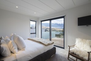 Relax in this serene bedroom with a large bed, flat-screen TV, and breathtaking views of the surrounding mountains and water.