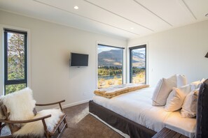 Enjoy breathtaking mountain views from the large bed, with a flat-screen TV and plush chair nearby.