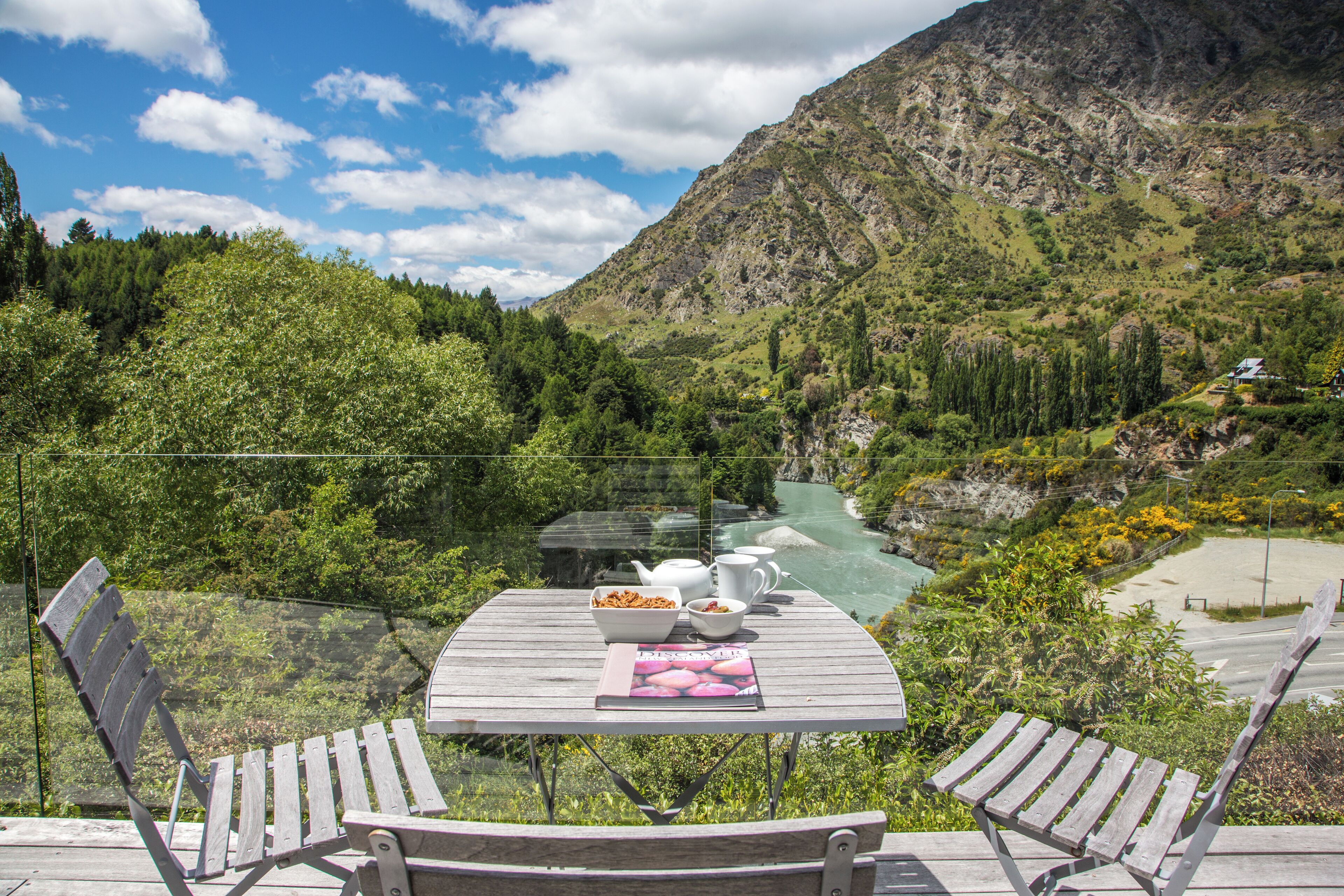 A wooden table with a view of a river and mountains.