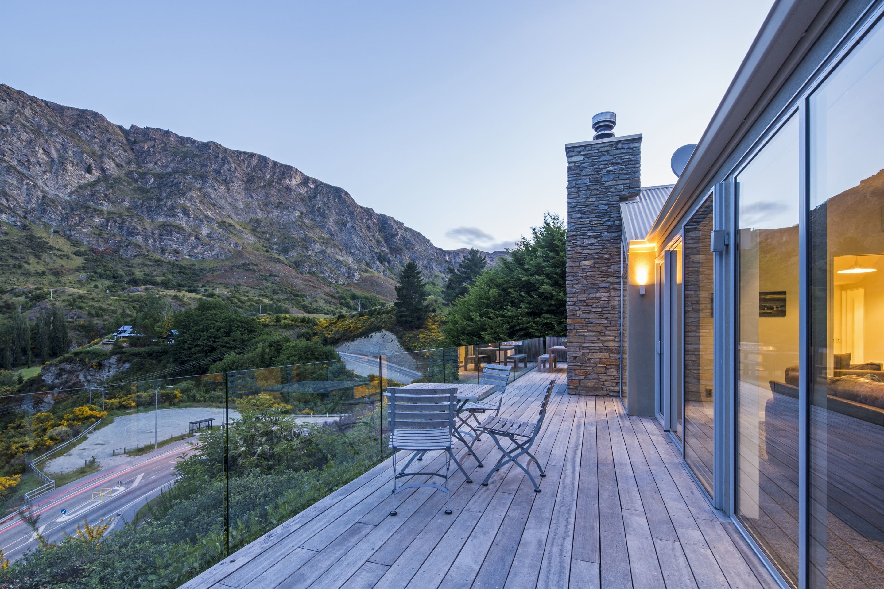 A modern building with a wooden deck, stone wall, and glass doors.