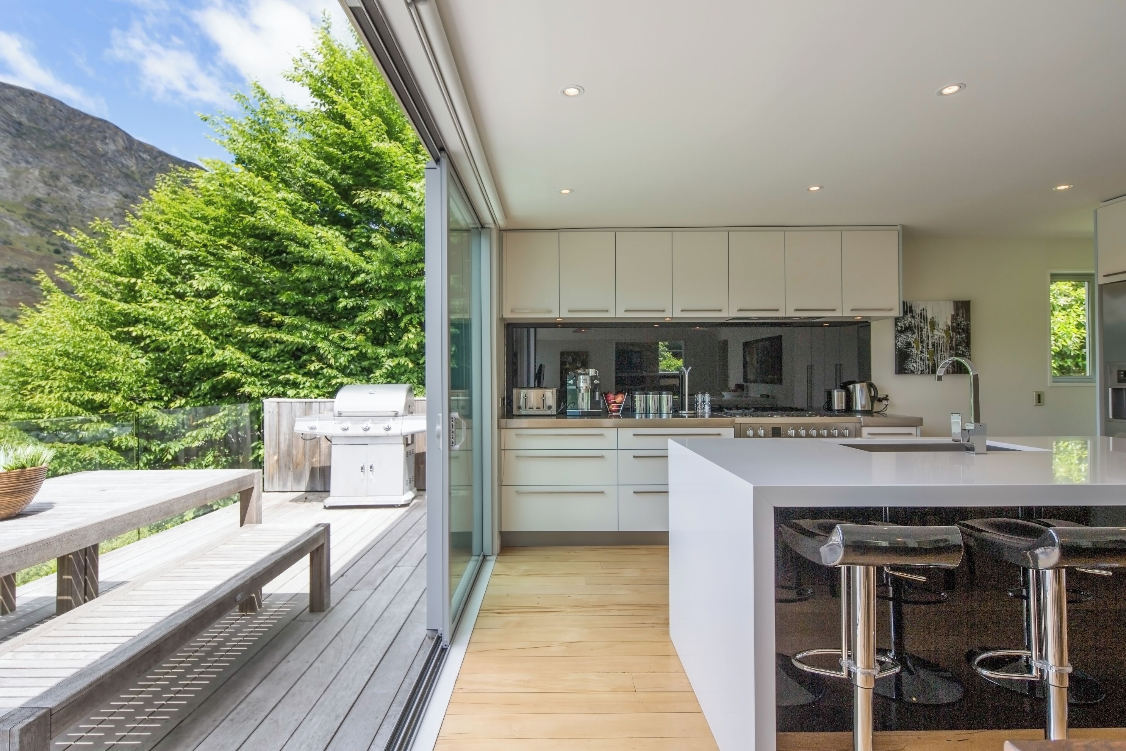 A modern kitchen with a large island, bar stools, and a view of a mountain.