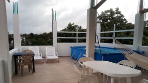 Un espacio exterior cubierto con piscina, sillas de descanso y una mesa.