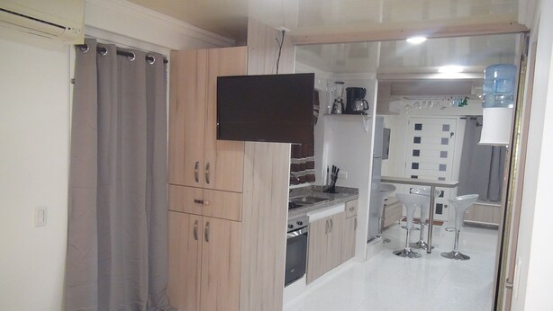 Una cocina compacta con horno integrado, cafetera y dispensador de agua.