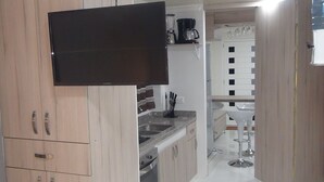 Una cocina moderna con armarios de madera, horno empotrado y televisor de pantalla plana.