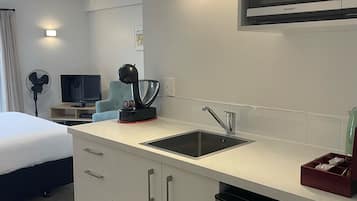 Una cocina moderna con un lavamanos negro, electrodomésticos de acero inoxidable y un microondas encima.