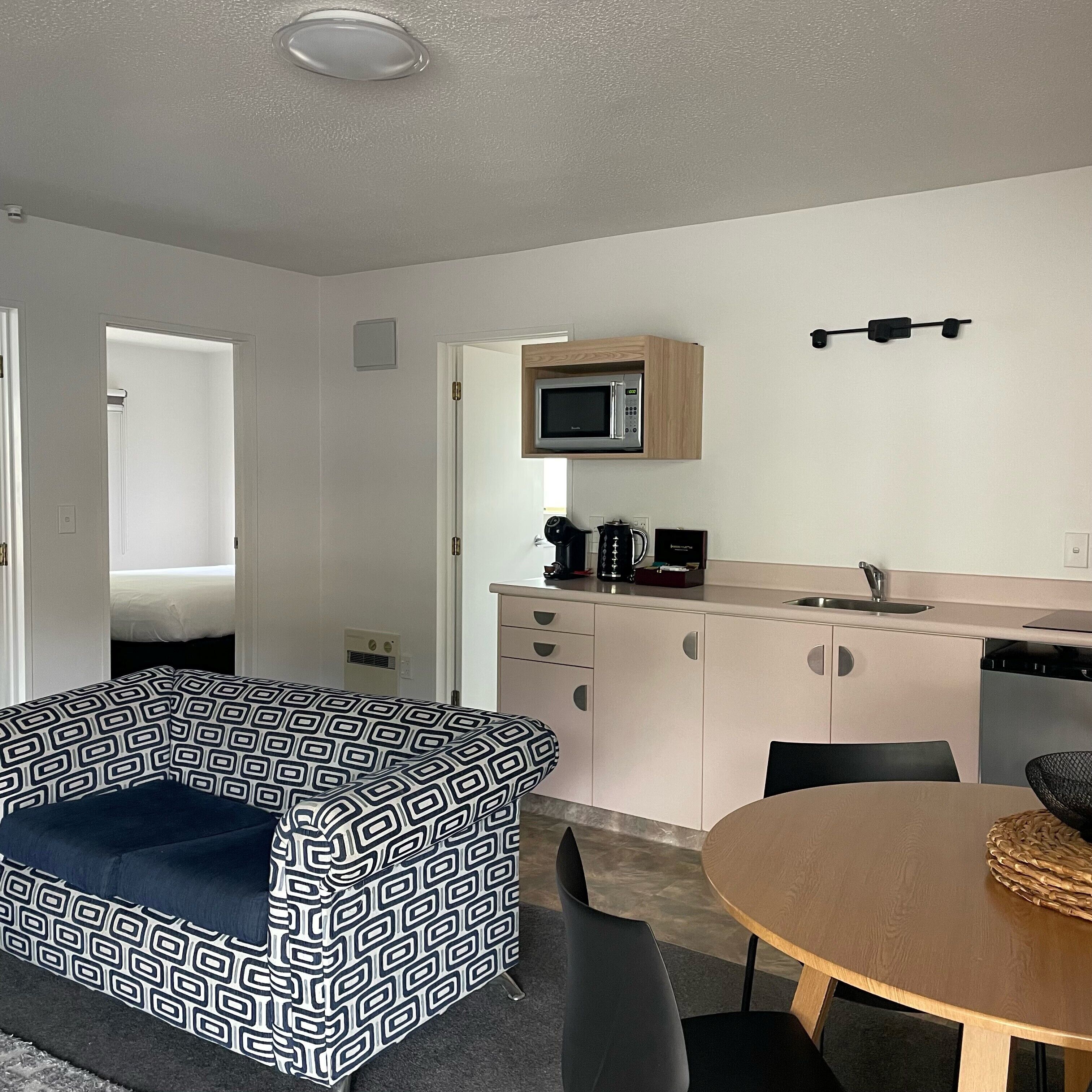 A compact living space with a kitchenette, a dining area, and a bedroom.