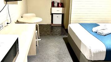 Ein Hotelzimmer mit Bett, Schreibtisch mit Computer, kleinem Kühlschrank, Mikrowelle und Fernseher.