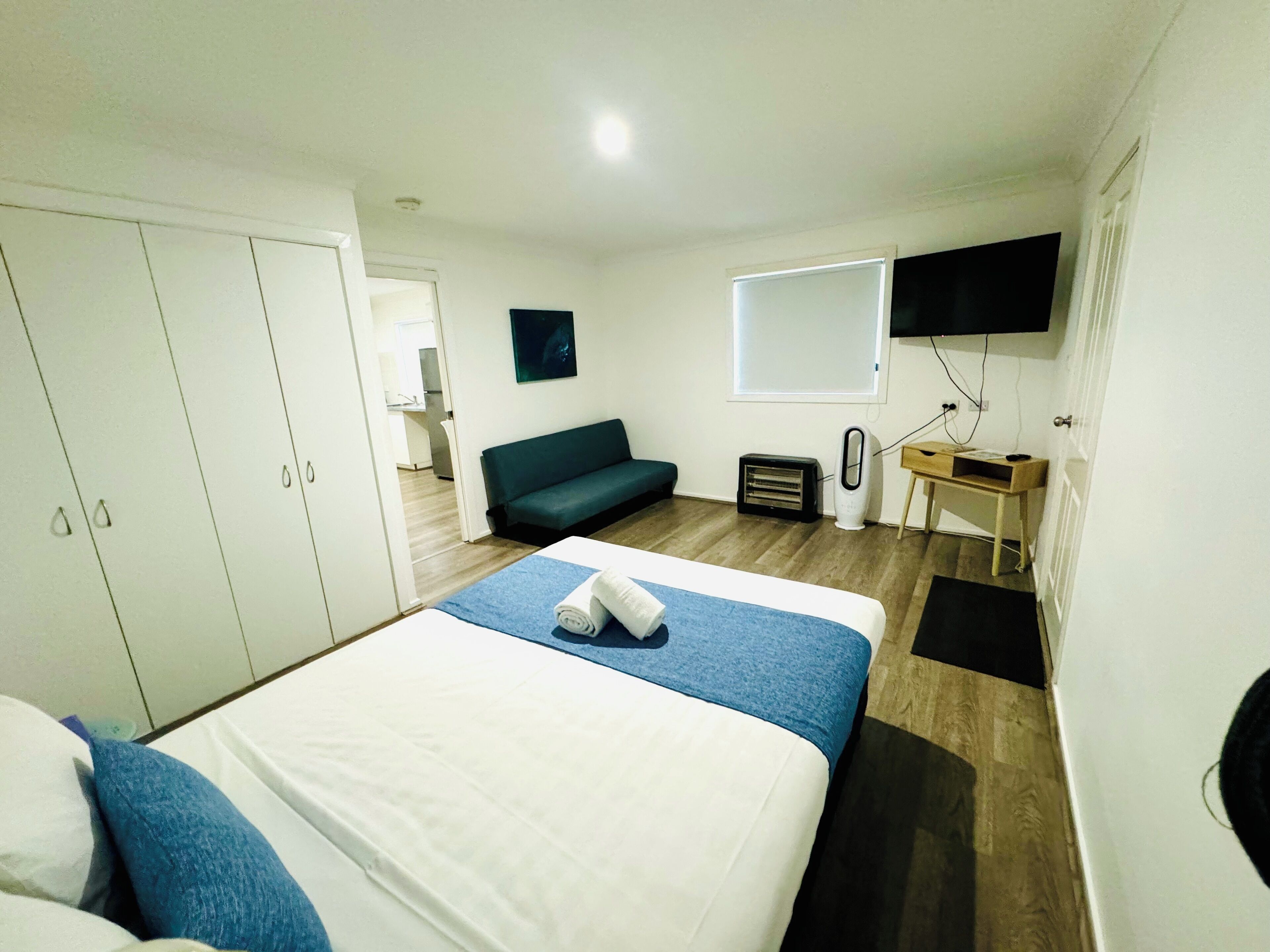 Ein Hotelzimmer mit Bett, einer Couch, einem Schreibtisch und einem Fernseher.