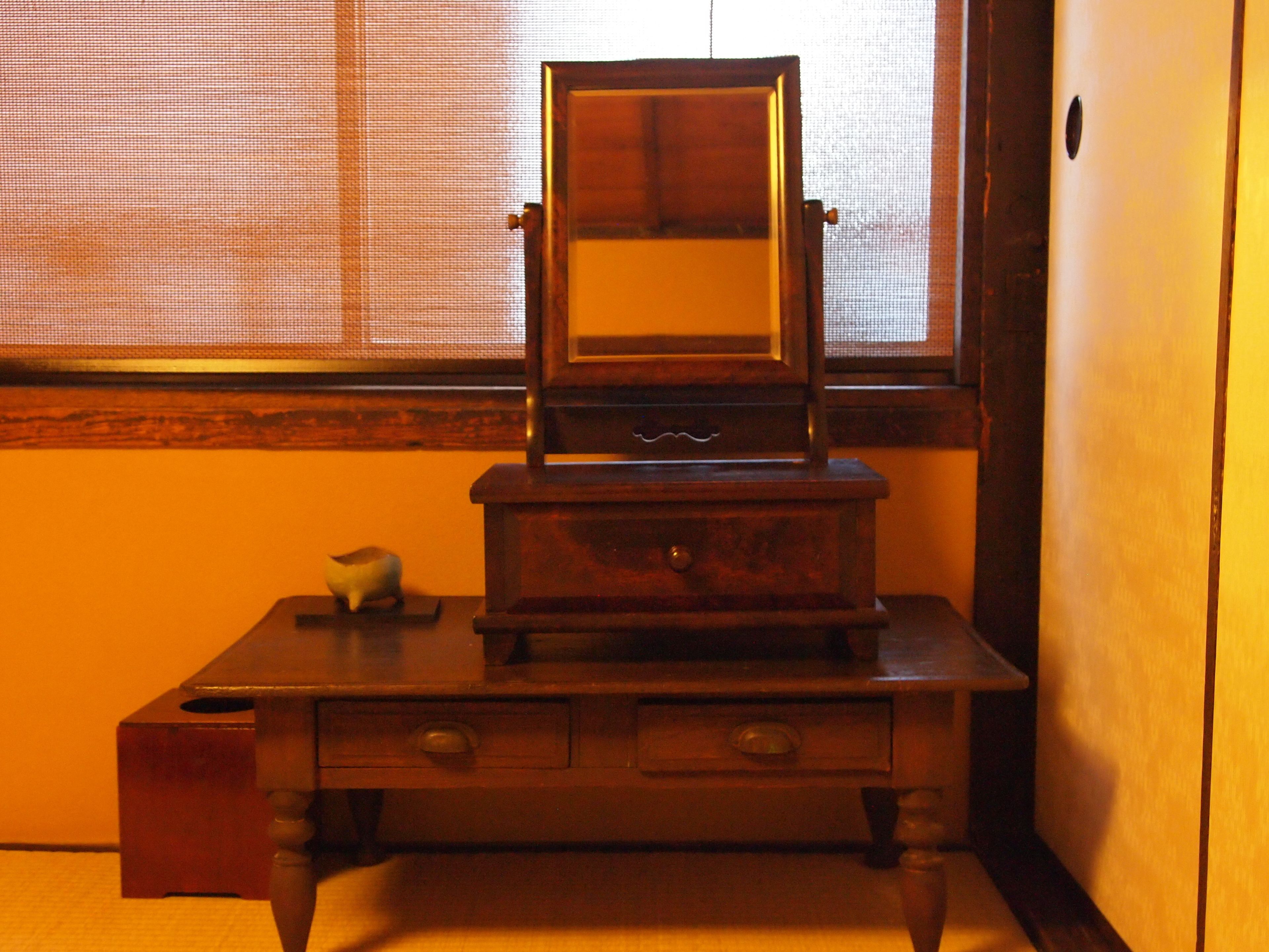 A wooden dresser with a mirror, drawers, and a small decorative item.