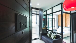Una habitación de hotel moderna con un ventanal grande, un sofá y una lámpara colgante roja.