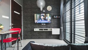 Una sala de estar moderna con televisor, ventilador y un reloj en la pared.