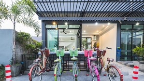 Un edificio moderno con vestíbulo cubierto, bicicletas estacionadas al frente y una escalera visible que conduce a la entrada.
