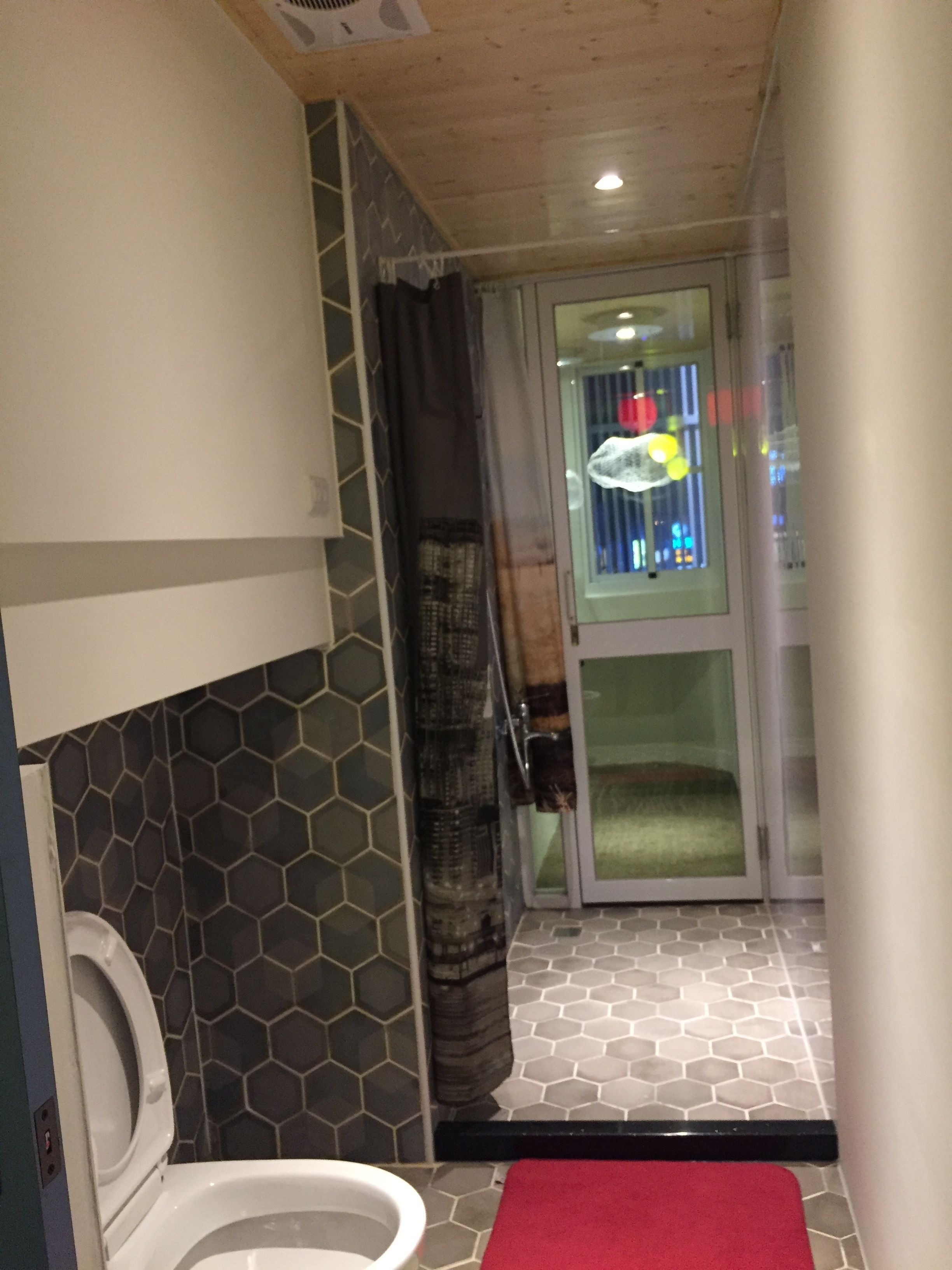 A compact bathroom with a toilet, a shower area, and a glass door leading to a balcony.
