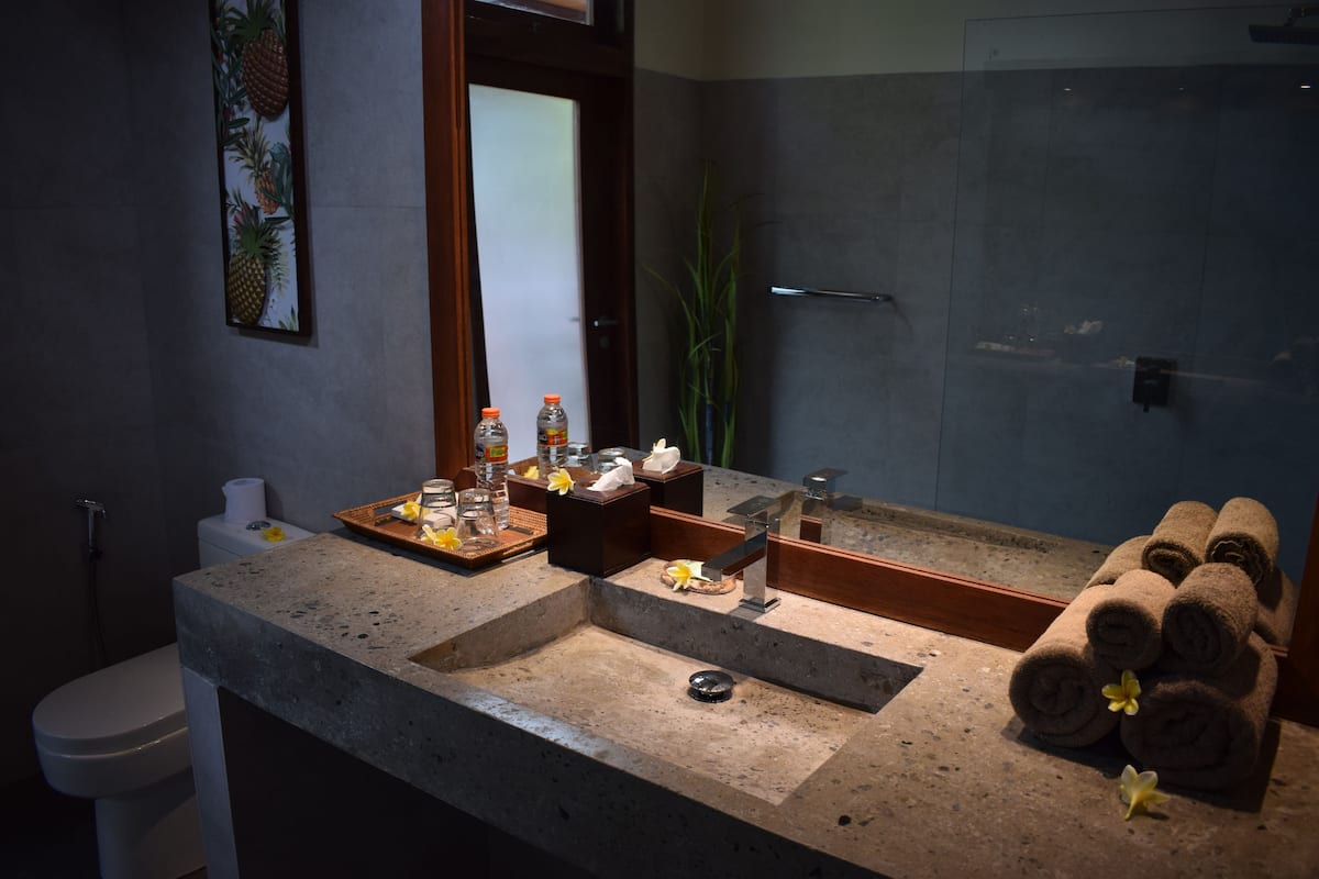 A bathroom with a large mirror, a sink, and a toilet. There are towels and toiletries on the counter.