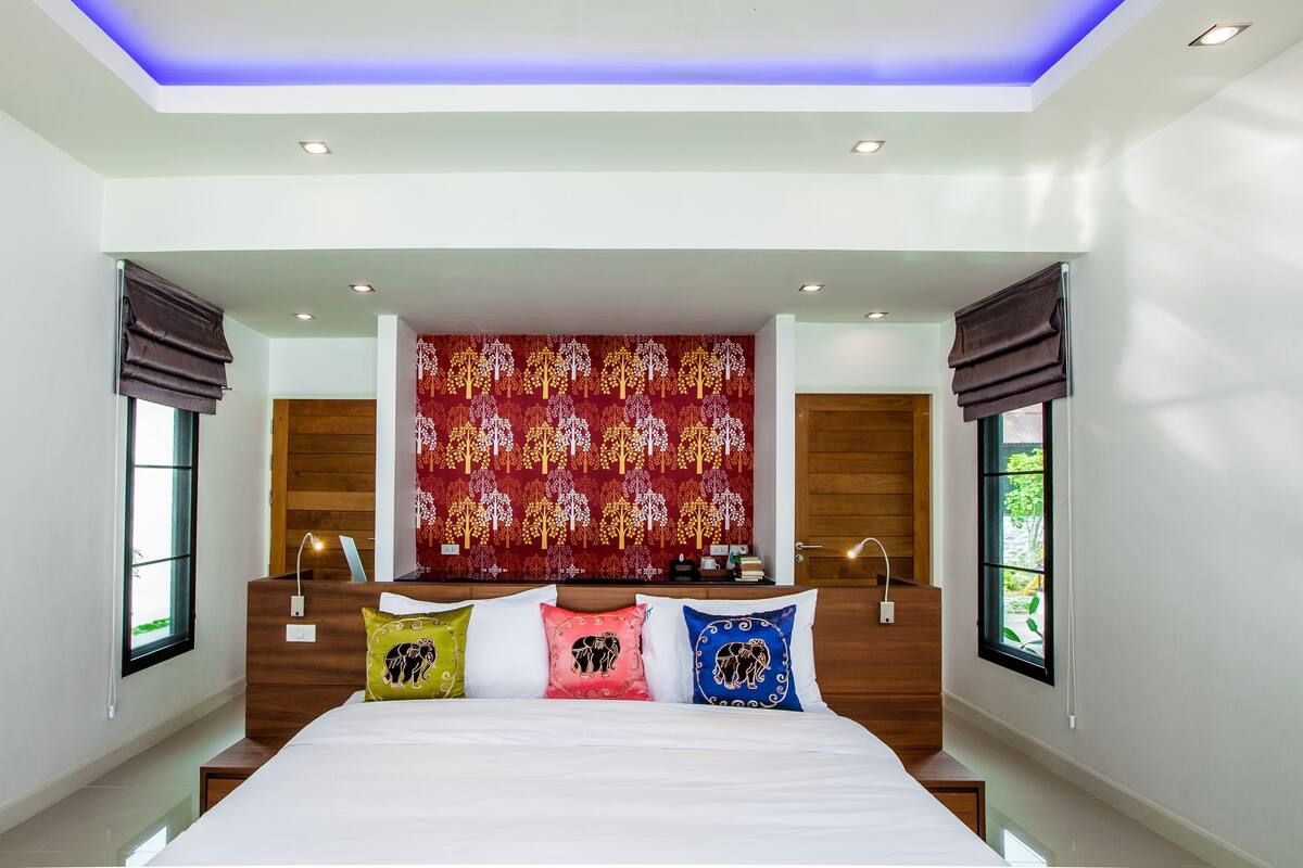 Une chambre moderne avec un grand lit, une tapisserie à motifs et un luminaire au plafond.