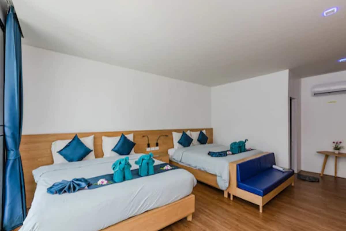 Une chambre d’hôtel avec deux lits, des têtes de lit en bois et une petite table sur laquelle est posée une plante.