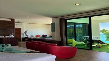Une chambre d’hôtel moderne avec un lit, un canapé rouge et une vue sur une piscine et un espace verdoyant.