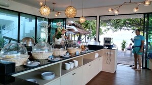 Een ontbijtbuffet met afgedekte etalages, een koffiehoek en uitzicht op het omliggende landschap.