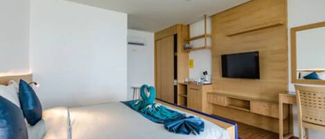 Una habitación de hotel moderna con una cama grande, un escritorio, un televisor y un armario de madera.