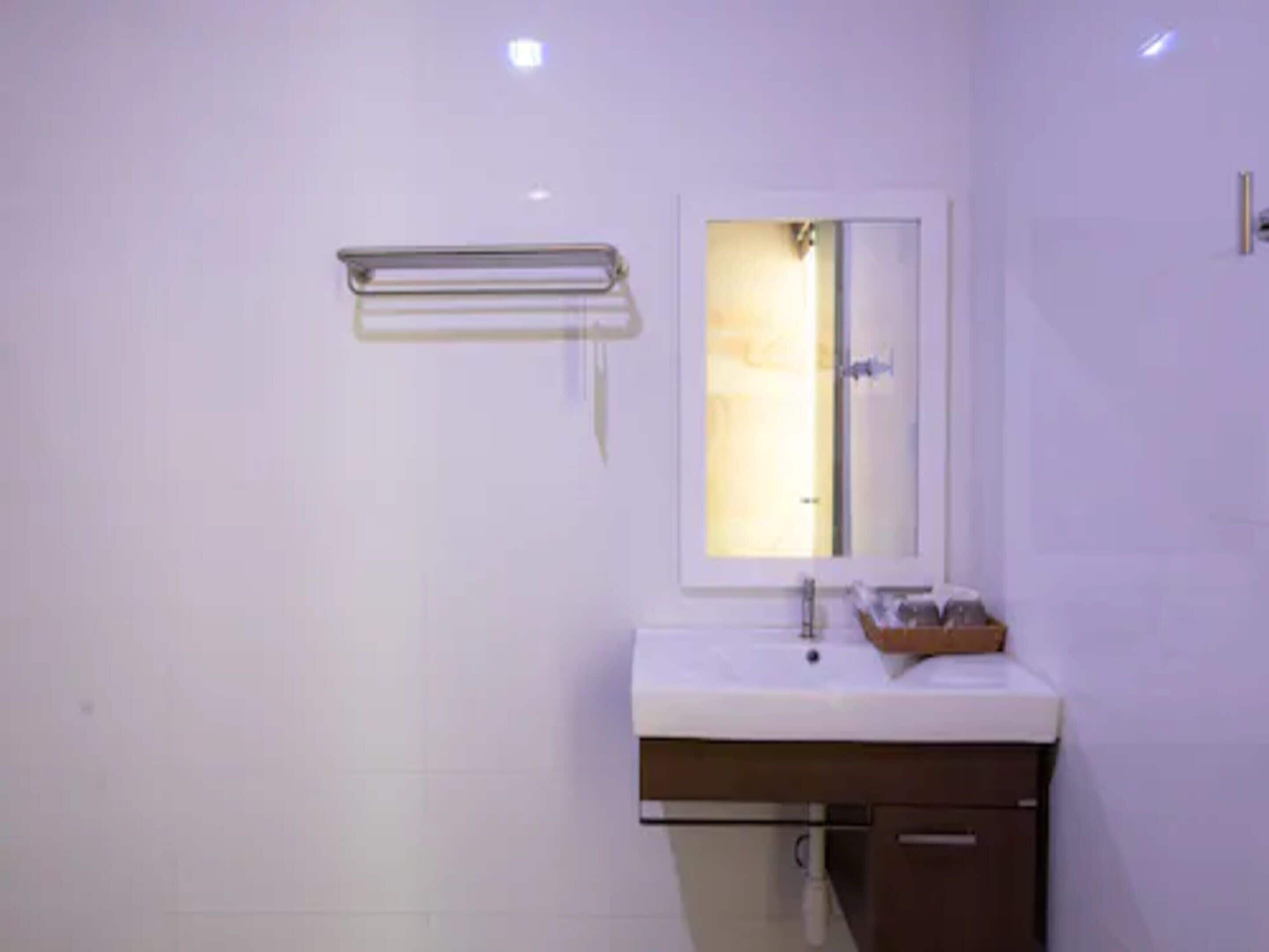 A modern bathroom with a white sink, a mirror, and a towel rack.