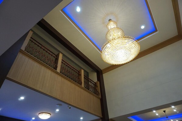 Un candelabro con techo iluminado en azul, paneles de madera y un balcón con barandillas ornamentales.
