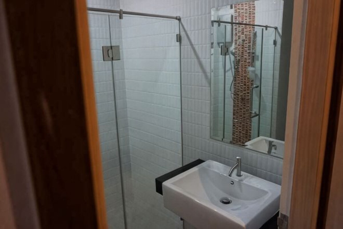 Un baño con cabina de ducha de vidrio, lavamanos y espejo.