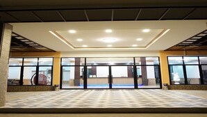 A hotel entrance with a tiled floor, glass doors, and a ceiling with recessed lighting.