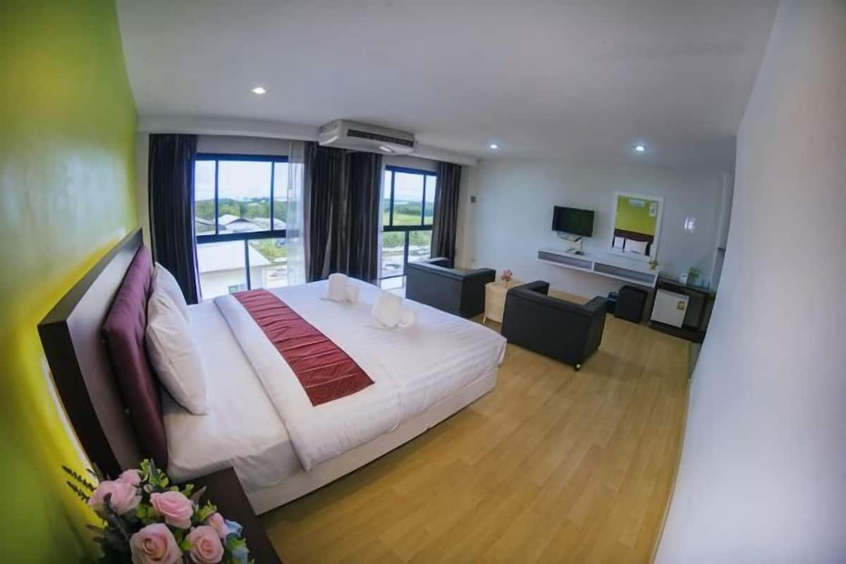 A hotel room with a large bed, a desk, a chair, a TV, and a window with a view.